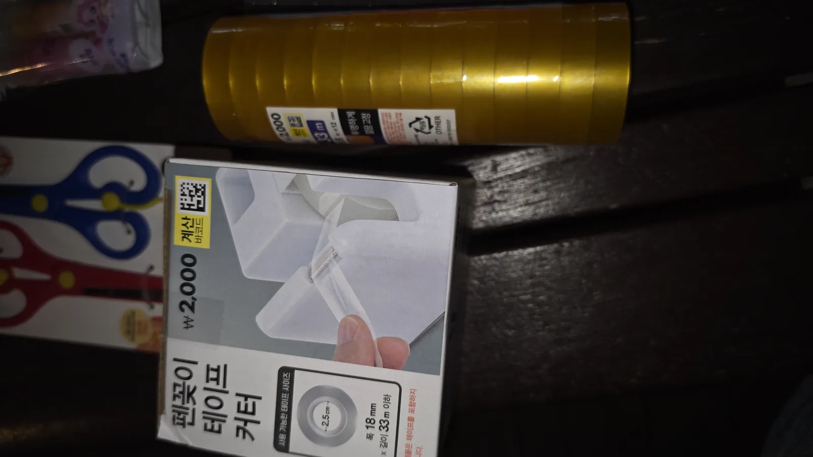 금색 포장지에 감싸인 투명 테이프 묶음과 테이프 커터 상자