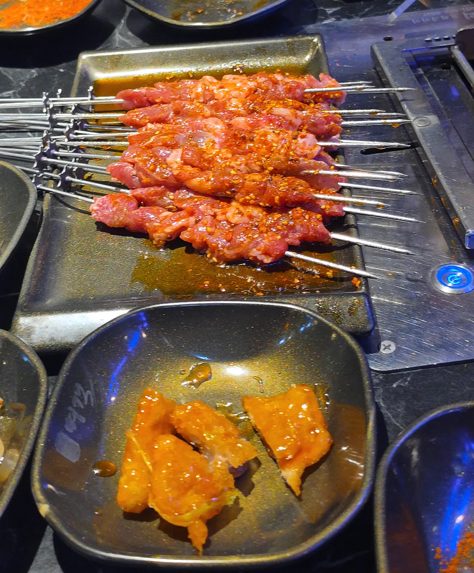 빨간 양념 양꼬치 한 판과 작은 접시에 담긴 꿔바로우 몇 점